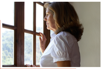 A woman standing, looking out a window