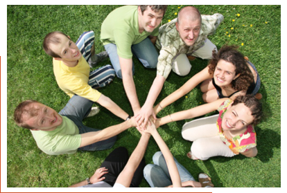 A circle of people with their hands placed together in the center of the circle